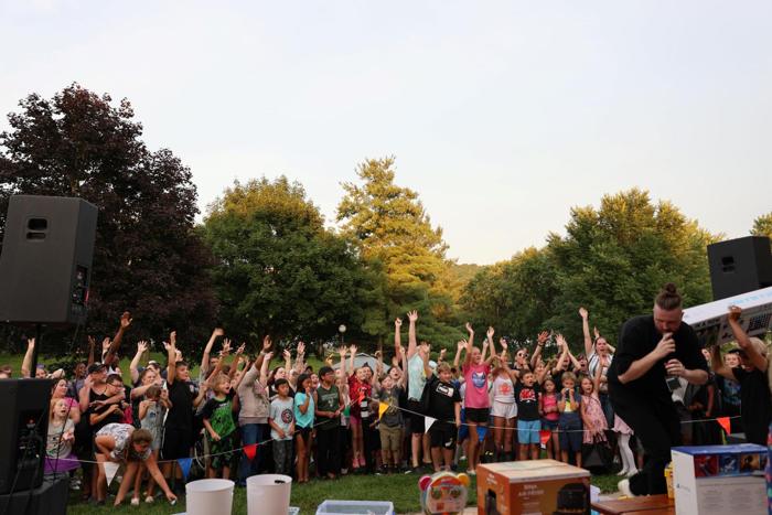 Children with hands up in front of the sound system at dusk