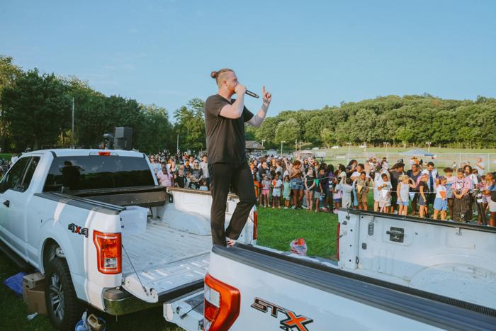 Preaching from the bed of a pickup truck to a crowd in a park