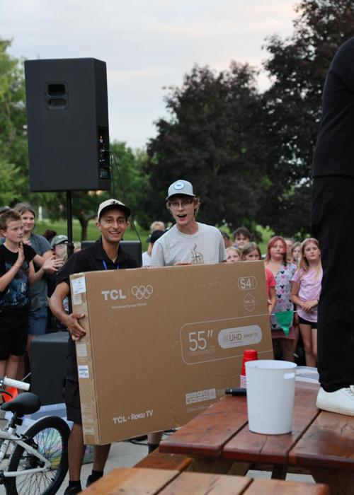 Two men holding up a TV prize at an outreach giveaway