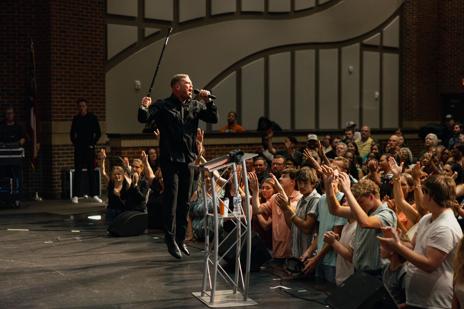 Preacher at the pulpit with the crowd standing and worshiping