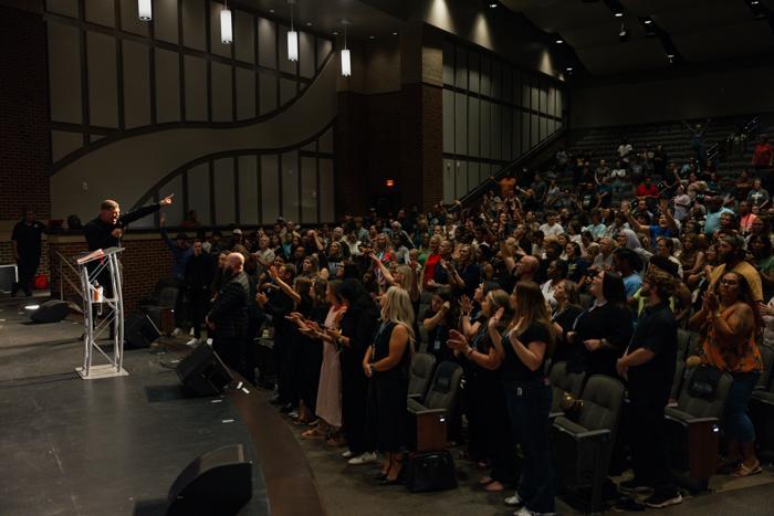 Crowd with hands raised at an indoor revival meeting