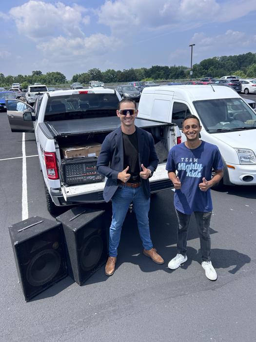 Josh and a friend beside a pickup loaded with speakers