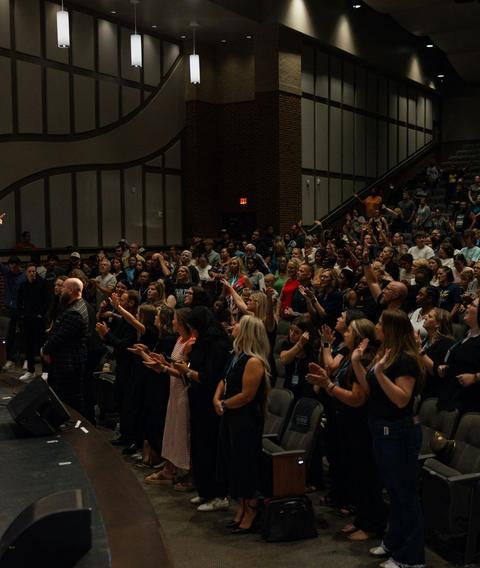Crowd with hands raised at an indoor revival meeting