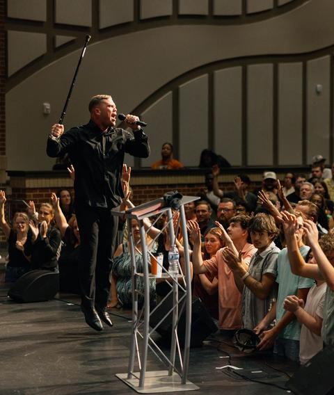 Preacher at the pulpit with the crowd standing and worshiping