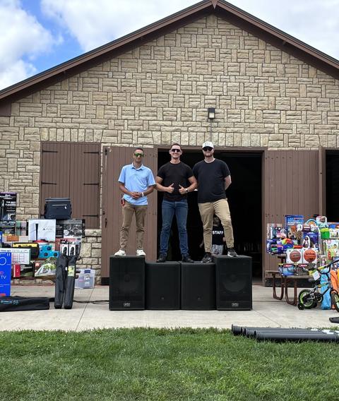 Team setting up sound and giveaways in front of a park building