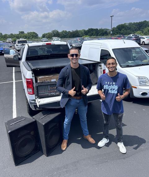 Josh and a friend beside a pickup loaded with speakers